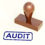the word audit and a wooden stamp