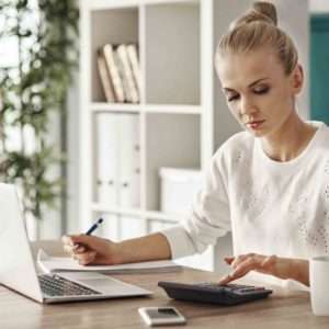 woman budgeting on calculator and laptop